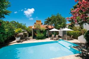 una piscina en un patio con sillas y sombrillas en Pousada Castanheira, en Natal
