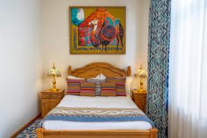 1 dormitorio con 1 cama y una pintura en la pared en Navat Hotel, en Bishkek