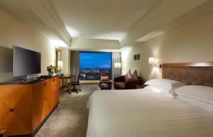 a hotel room with a bed and a flat screen tv at The Splendor Hotel Taichung in Taichung