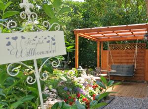 a sign in a garden with a swing and flowers at Bülows kleines Ferienhaus in Thiessow