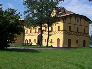 a large yellow building with a tree in front of a field at Corte Degli Estensi in Formigine