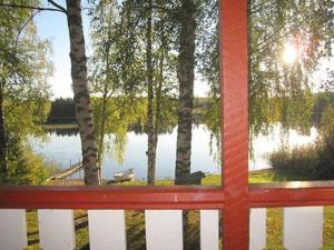 a red bench in front of a lake with trees at Holiday Home Viljamaan lomamökit 2 by Interhome in Vaskivesi