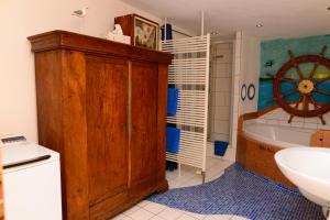ein Badezimmer mit einem Holzschrank, einer Badewanne und einem Waschbecken in der Unterkunft Ferienwohnung Traumschiff in Erzingen