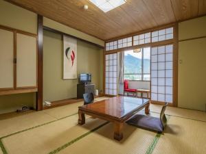 een woonkamer met een tafel en een stoel bij Kurobe View Hotel in Omachi