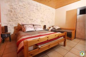 1 dormitorio con cama de madera y pared de piedra en Gîte La Morandière, en Saint-Martin-en-Vercors
