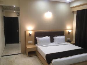 a bedroom with a large bed with white sheets and pillows at Hotel Aarunya Royale in Jodhpur