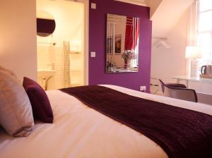 una camera da letto con un grande letto con pareti viola di Guestling Hall Hotel a Guestling