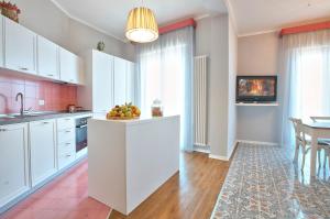 a kitchen with white cabinets and a table with a bowl of fruit at B&B Del Corso in Capo dʼOrlando