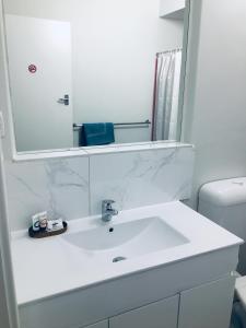 La salle de bains est pourvue d'un lavabo blanc et d'un miroir. dans l'établissement The Sands Motel Adelaide, à Adélaïde