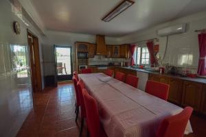 a kitchen with a long table and red chairs at Monte dos Rolas in Alcácer do Sal