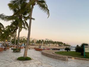 a beach with palm trees and tables and chairs at Purple Lily Studio Hawana Lagoons Salalah in Salalah
