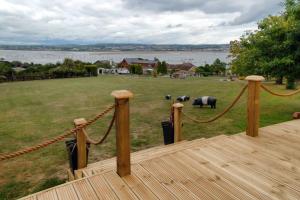 a deck with a rope fence and elephants in a field at Violet Mays Retreat in Starcross