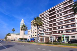 un grand bâtiment blanc avec une tour d'horloge et des palmiers dans l'établissement Mosquee & Sea View Casablanca, à Casablanca