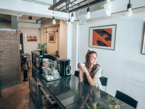 a woman sitting at a counter with a cup of coffee at Haus Sathorn 11 Residence in Bangkok
