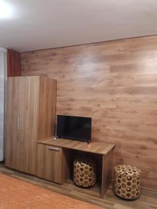 Habitación con pared de madera y TV. en Private Rooms Silvia, en Varna