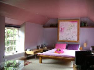 a bedroom with purple walls and a bed with a flower on it at The Wookey Hole Inn in Wells