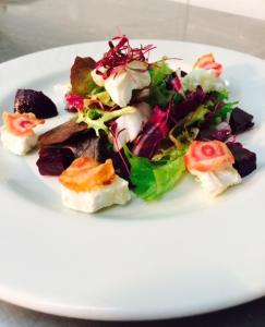 a white plate with a salad on a table at The Wookey Hole Inn in Wells