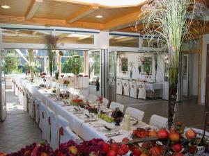 une grande salle à manger avec des tables et des chaises blanches dans l'établissement Hotel Gasthof Buchbauer, à Bad Sankt Leonhard im Lavanttal