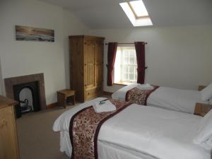 Habitación de hotel con 2 camas y chimenea en DAIRY MAIDS COTTAGE, en Seascale