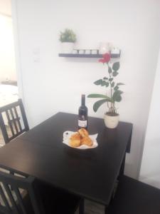 una mesa negra con una botella de vino y un plato de donuts en Rozinka apartman, en Dunaújváros