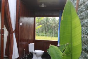 a bathroom with a toilet and a window at Mancur Guesthouse in Ubud