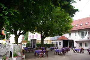 un groupe de tables et de chaises dans une cour arborée dans l'établissement Hotel Gaum, à Biberach-Ummendorf