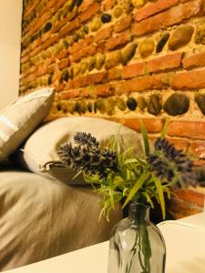 a vase with flowers on a table next to a brick wall at L' Appart in Toulouse