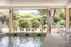 a woman in a white robe standing in front of a pool at La Villa Calvi in Calvi