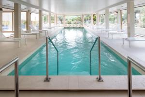 uma grande piscina com cadeiras brancas num edifício em La Villa Calvi em Calvi