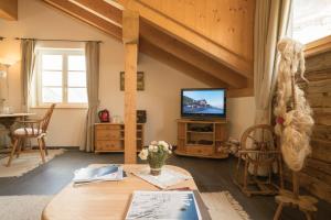a living room with a table and a tv at Gasthaus & Hotel Berninahaus in Pontresina