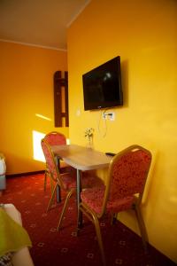 a room with a table and chairs and a tv at Pokoje i Apartamenty Pod Akacjami in Malbork