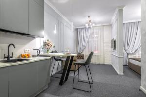 a kitchen with white cabinets and a table and chairs at Staronevsky Dom in Saint Petersburg