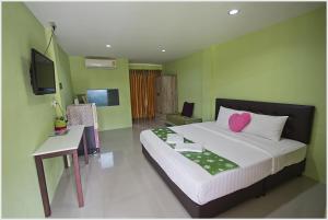 a bedroom with a bed and a desk and a television at บ้านทิพรัตน์ สัตหีบ in Sattahip