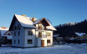 a white house with snow on the roof at Hołdysówka przy Gondoli in Szczyrk