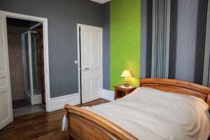 1 dormitorio con cama y pared verde en La Dragée Hôte, Chambres chez l'habitant, en Verdún