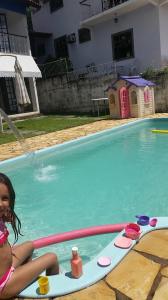 een klein meisje op een surfplank in een zwembad bij Pousada Pedacinho do Céu in Conservatória