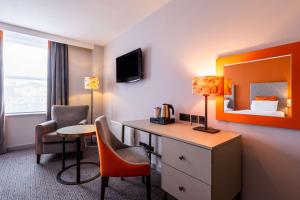a hotel room with a desk and a bed at Cedar Court Hotel Harrogate in Harrogate