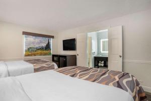 a hotel room with two beds and a television at Baymont by Wyndham Montgomery AL in Montgomery