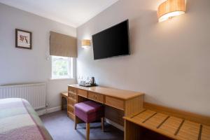 a bedroom with a bed, desk and television at Makeney Hall Hotel in Derby