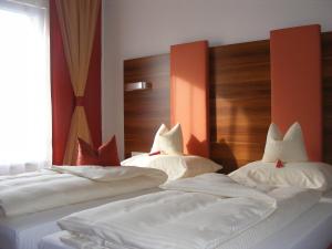 two beds with white sheets and red pillows at Hotel Gaum in Ummendorf-Biberach