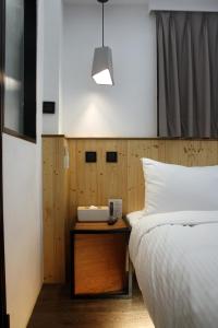 a bedroom with a bed and a table with a phone at Just Inn Taipei (Xin Yi) in Taipei