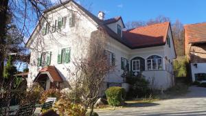 ein weißes Haus mit rotem Dach und grünen Rollläden in der Unterkunft Hirschenhof in Graz