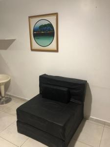 un sofá negro en una habitación con una foto en la pared en Apartamento Tambaú, en João Pessoa