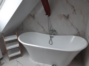 a white bath tub in a bathroom with marble walls at POD DĘBEM in Cerkiewnik
