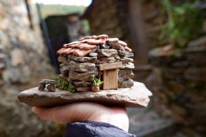 una mano sosteniendo una pequeña casa en un trozo de roca en Cerdeira - Home for Creativity, en Lousã