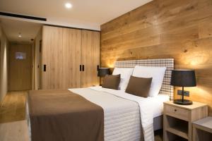 1 dormitorio con 1 cama blanca grande y paredes de madera en Korona, Resort & Entertainment, en Kranjska Gora