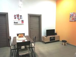 een eetkamer met een tafel en een tv bij Theatron Houses- Centro Storico in Catania