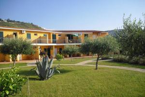 Marasusa Tropea في بارغيليا: مبنى اصفر كبير فيه اشجار في ساحة