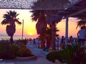 a group of people standing on the beach at sunset at Sunset Studios & Rooms in Antiparos