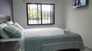 Hotel Tazumal House في سان سلفادور: غرفة نوم بسرير وبطانية ونافذة